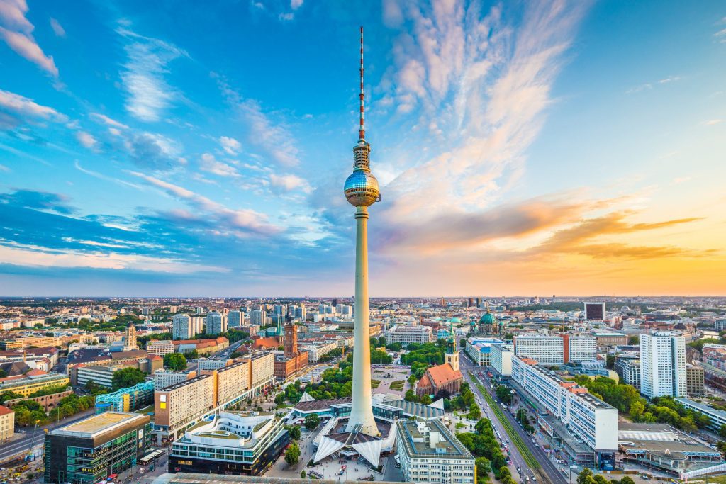 Berliner Fernsehturm am Alexanderplatz, umgeben von der Innenstadt, bei farbigem Abendhimmel.