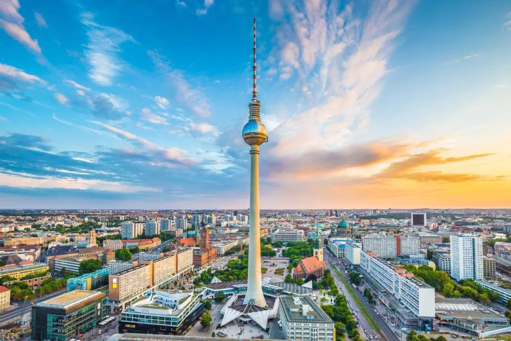 Berliner Fernsehturm am Alexanderplatz, umgeben von der Innenstadt, bei farbigem Abendhimmel.