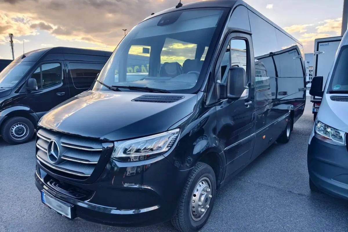 Schwarzer Mercedes-Minibus auf einem Parkplatz bei Sonnenuntergang.