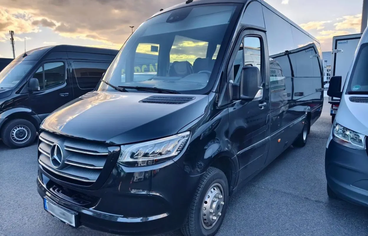 Schwarzer Mercedes-Minibus auf einem Parkplatz bei Sonnenuntergang.