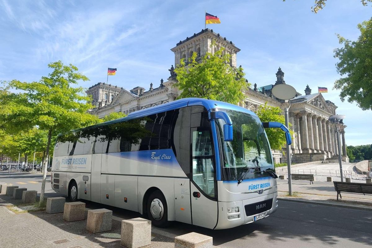 Reisebus von Fürst Reisen Berlin vor dem Reichstagsgebäude bei sonnigem Wetter.