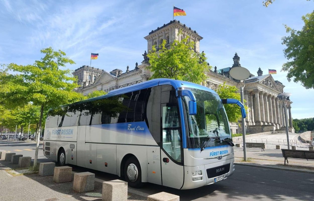 Reisebus von Fürst Reisen Berlin vor dem Reichstagsgebäude bei sonnigem Wetter.